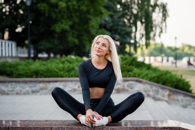 Healthy sports lifestyle. Young beautiful woman in a sports wear sit in city park