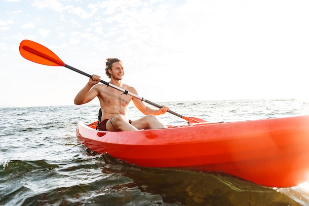 Healthy strong man kayaking on a sea