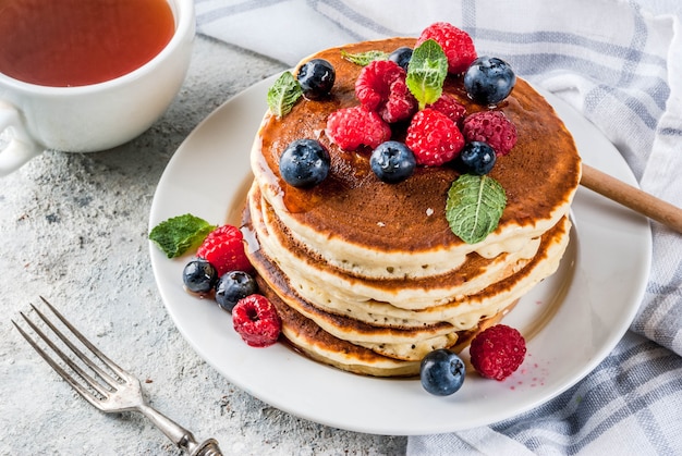 Healthy summer breakfast,homemade classic american pancakes with fresh berry and honey, morning light grey stone surface 