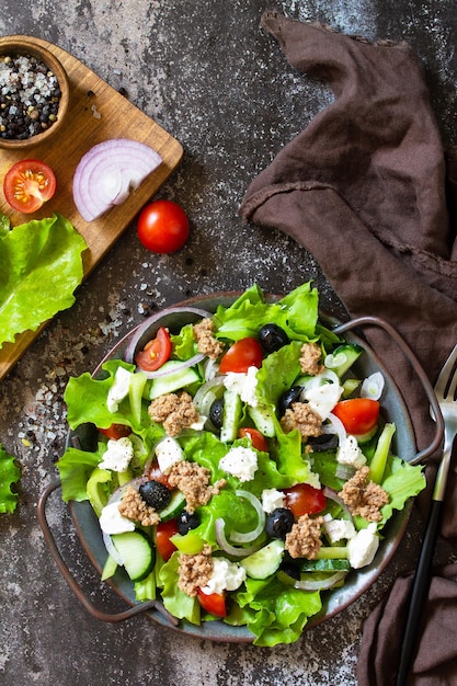 Healthy summer lunch Greek salad with canned tuna vegetables and lettuce on a stone countertop