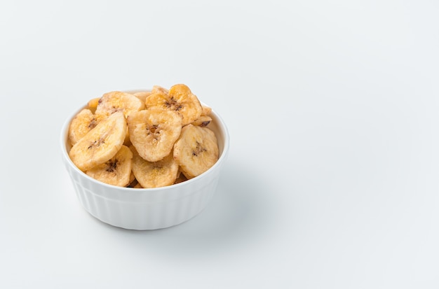 Healthy sweets, pieces of dried banana in a bowl on a light background