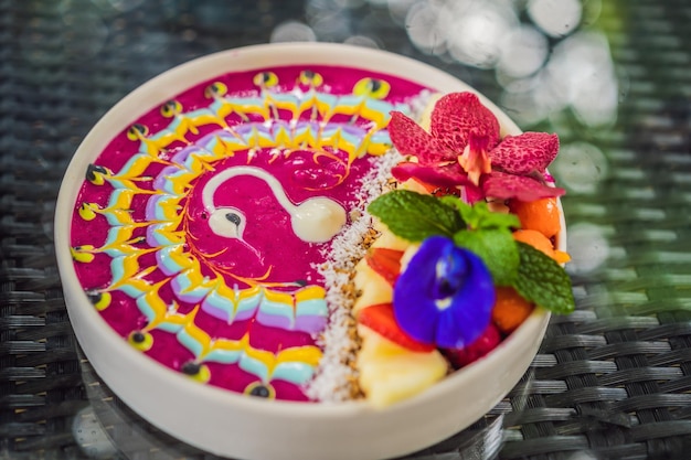 Healthy tropical breakfast smoothie bowl with tropical fruits decorated with a pattern of colorful