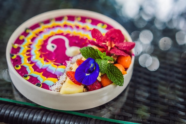 Healthy tropical breakfast smoothie bowl with tropical fruits decorated with a pattern of colorful