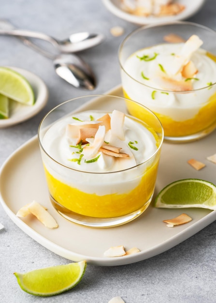 Healthy tropical cream cheese dessert with mango puree and roasted coconut chips in a glass jar