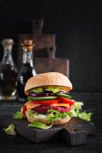 Healthy vegan beetroot burgers with tomato, cucumber, red onion and sauce. Dark background. Copy space.