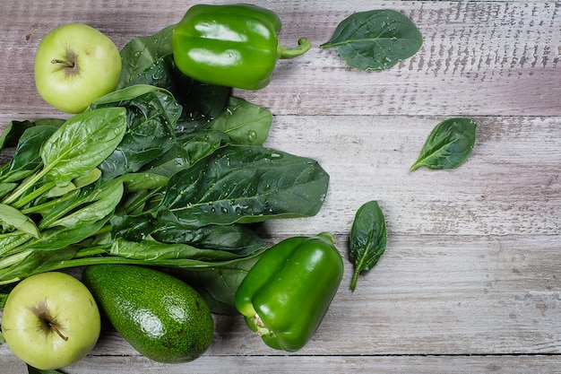 Healthy Vegan Food. Collection of green vegetables on wooden background, peppers, apple