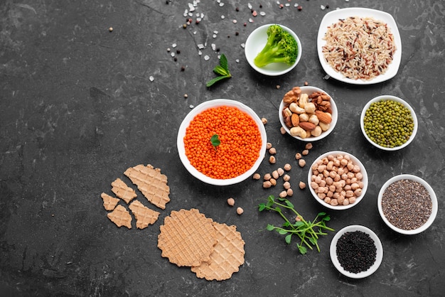 Healthy vegan food on a concrete background with copy space. Nuts, beans, greens and seeds