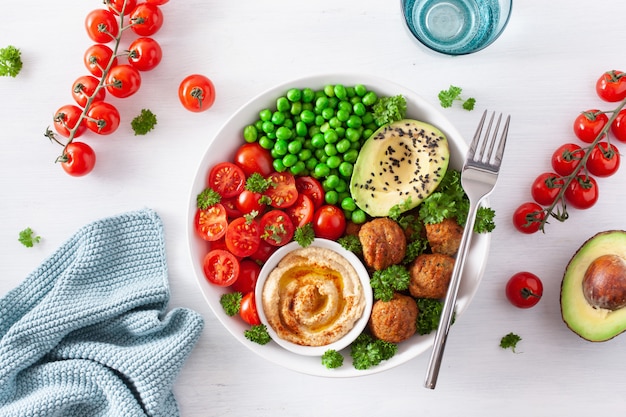 Healthy vegan lunch bowl with falafel hummus tomato avocado peas