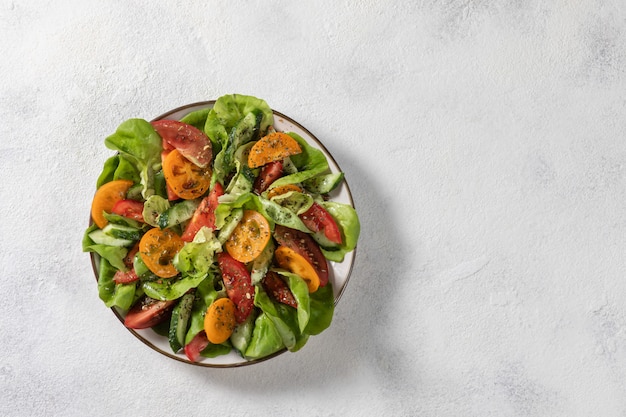 Healthy vegetable salad from fresh vegetables of tomatoes, cucumbers, onions, spinach, lettuce on a plate. Diet menu. View from above.