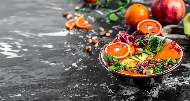 Healthy vegetarian buddha bowl salad with avocado persimmon blood orange nuts spinach arugula and pomegranate on a light background Long banner format top view