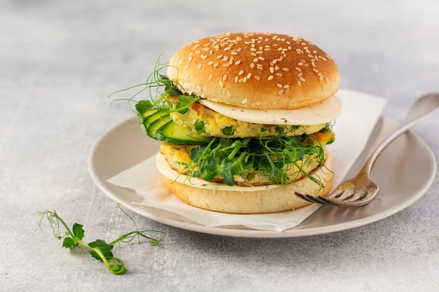 Healthy Vegetarian burger with egg and pea shoots and seeds microgreen, fresh salad, cucumber slice on a cutting wooden board on light background. Selective focus