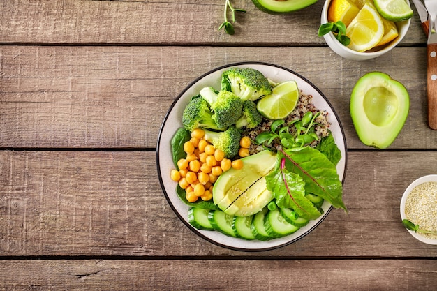 Healthy vegetarian food concept: quinoa with vegetables, seeds and herbs on wooden background. Top view.