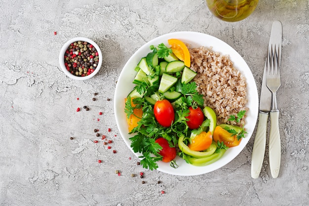 Healthy vegetarian salad of fresh vegetables, tomatoes, cucumber, sweet peppers and porridge