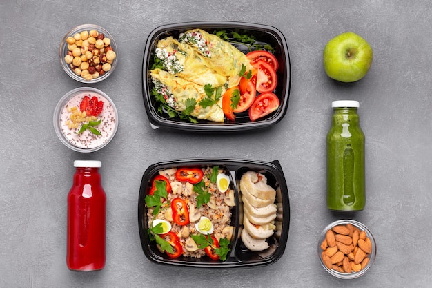 Healthy well balnced food. Plastic boxes with fresh meal, almond, hazelnut, tomato juices, apple, yogurt with chia seeds on wooden table, top view, concept