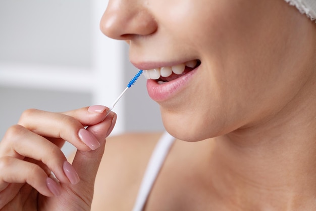 Healthy white teeth woman uses brushes to clean the interdental spaces