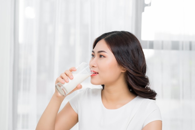 Healthy woman is drinking milk from a glass isolated on white background.