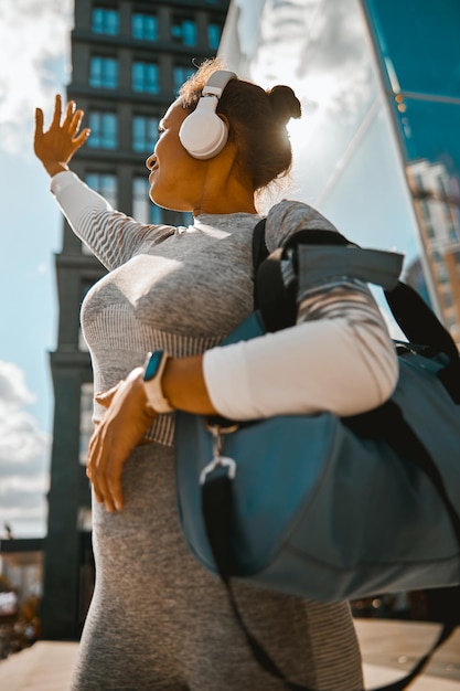 Healthy woman looking at the sun while standing near modern building in the city