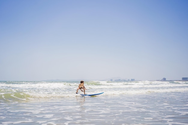 Healthy young boy learning to surf in the sea or ocean