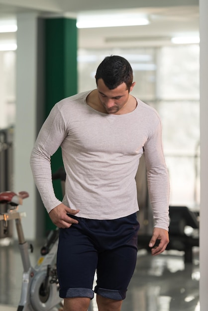 Healthy Young Man in White Tshirt Standing Strong and Flexing Muscles  Muscular Athletic Bodybuilder Fitness Model Posing After Exercises