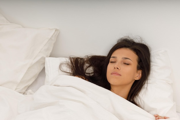 Healthy young woman covering white blanket sleep in bed at bedroom