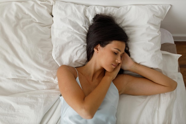 Healthy young woman dressing nightie lying on bed in bedroom