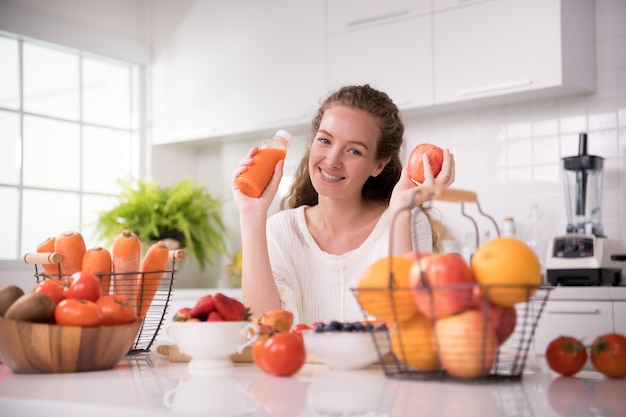 Healthy young woman in a kitchen with fruits and vegetables and juice