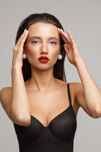 Healthy young woman in swimsuit poses for the camera and touchs her hair, picture isolated on white background