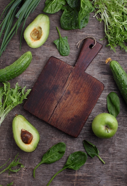 Healty green vegetable: spinach, cucumber, lettuce, apple and avocado on dark background. flat lay, copy space.