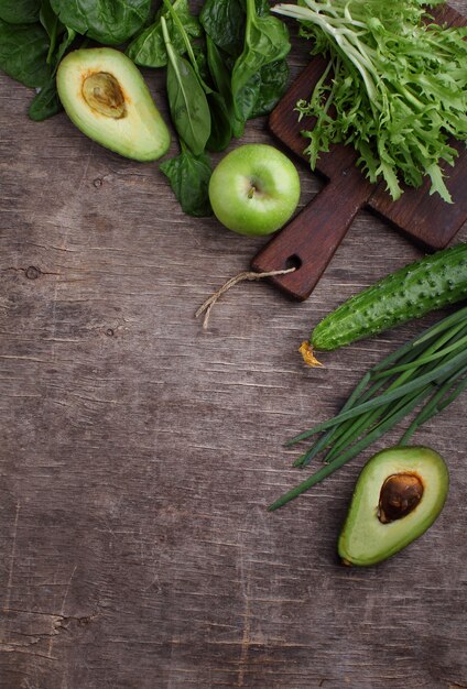 Healty green vegetable: spinach, cucumber, lettuce, apple and avocado on dark background. flat lay, copy space.