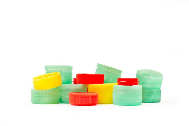 A heap of colored plastic bottle caps on a white background with copy space