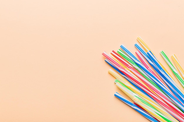 Heap of colorful plastic drinking straws on Colored background, flat lay. Copy Space for text