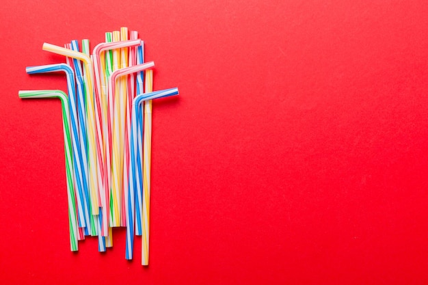 Heap of colorful plastic drinking straws on Colored background flat lay Copy Space for text