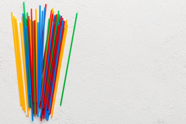 Heap of colorful plastic drinking straws on Colored background flat lay Copy Space for text