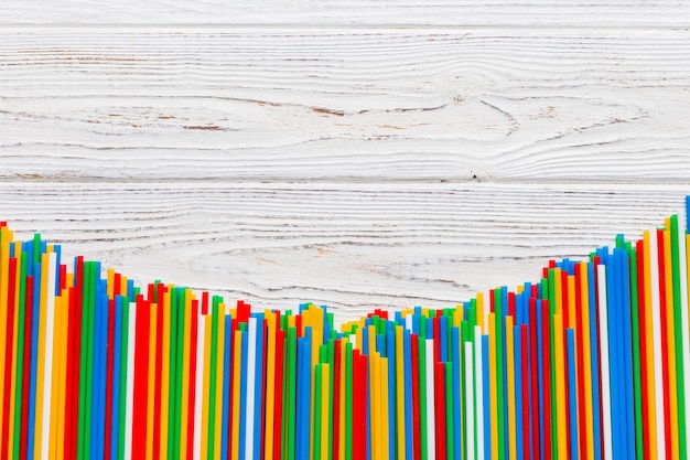 Heap of colorful plastic drinking straws on Colored background flat lay Copy Space for text