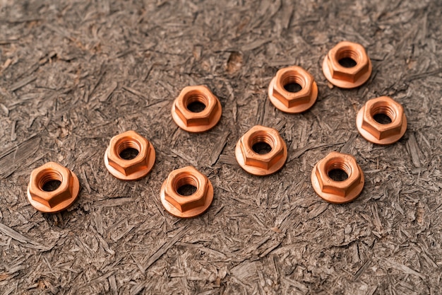 Heap of copper screw-nuts on wooden background.