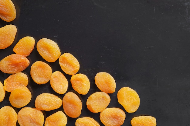 Heap of dried apricots on a black table