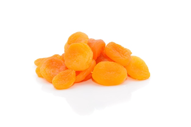 A heap of dried apricots on a white background with a light shadow viewed from above