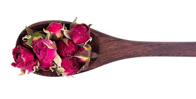 Heap of dry tea roses buds in wooden spoon isolated on white background Rose flower tea Phnom Penh rose tea Clipping path Top view