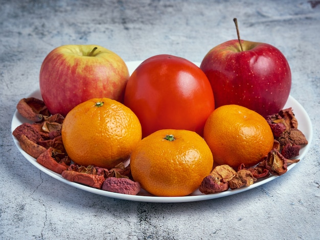 Heap of fresh seasonal apples, persimmon, mandarins and dried fruits