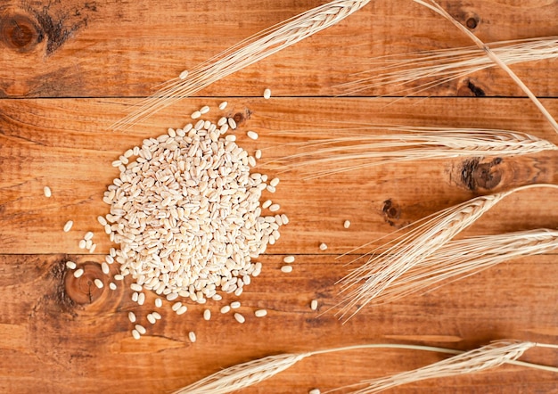 heap of grains with spikelets of wheat on a wooden surface. View from above