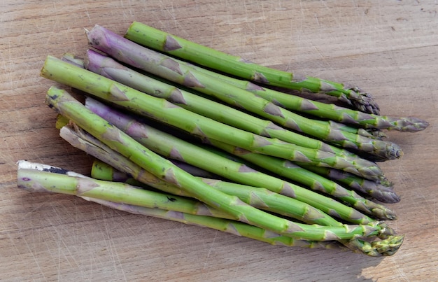 Heap of green raw asparagus put on a wooden table