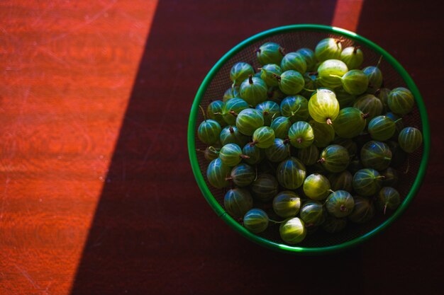 Heap of green washed gooseberry fruit in a colander on table top view