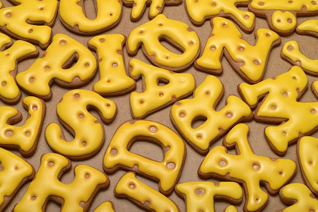 Heap of homemade yellow letters made from gingerbread biscuit background.