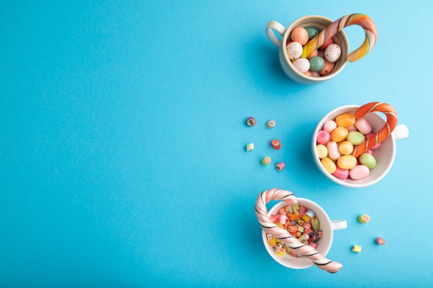 Heap of multicolored caramel candies in cups on blue pastel