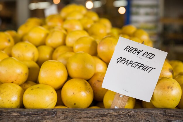 Heap of orange ruby grapefruit on a wooden table in the market with a sign