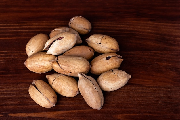 Heap of pecans with clipping path on a wooden background. Unpeeled pecans nut. Pecan nuts kernels