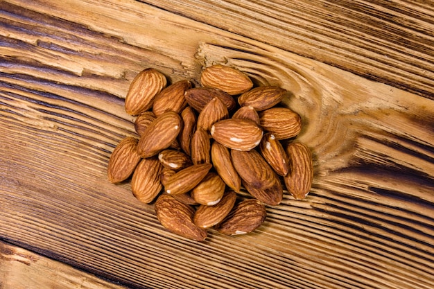 Heap of the peeled almond nuts on wooden table Top view