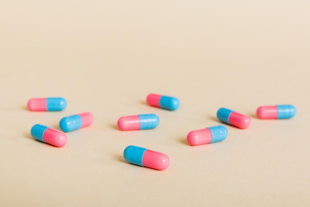 Heap of pink and blue pills on colored background Tablets scattered on a table Pile of red soft gelatin capsule Vitamins and dietary supplements concept