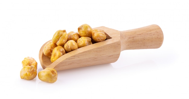 Heap of preserved chickpeas in wood scoop on white wall