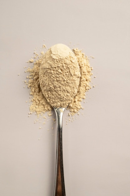 Heap of protein powder and a spoon with glass of water Food supplements